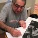 Jim Marshall signs his iconic Johnny Cash print for Brad Mangin in his San Francisco home on February 11, 2009. (Photo by Grover Sanschagrin)